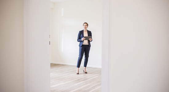 Woman dressed in business attire holding tablet in an open doorway